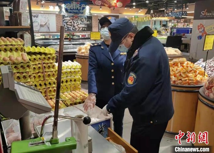 圖為疫情期間，甘肅嘉峪關(guān)市場監(jiān)管局工作人員檢查蔬菜市場?！?柴佳楠 　攝