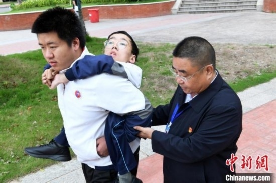 朱金祥背著鐘華強(qiáng)去教室上課的路上，也經(jīng)常碰到值班的校領(lǐng)導(dǎo)和老師前來搭把手。 卓忠偉 攝