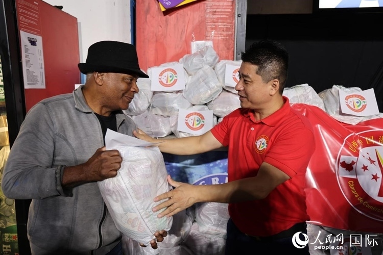巴西中國浙江商會會長鄭俠茂向社區(qū)居民轉(zhuǎn)交捐贈物資。人民網(wǎng)記者 時元皓攝