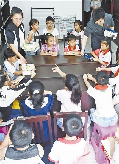  圖④：法院干警為留守兒童發(fā)放暑假讀物。