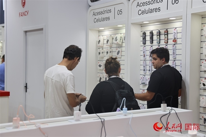 幾名參觀者在一個展臺前了解手機配件。（人民網(wǎng)記者 時元皓攝）