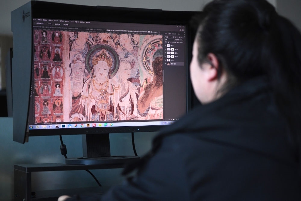 敦煌研究院文物數(shù)字化保護(hù)團(tuán)隊(duì)圖像處理人員年海麗在拼接壁畫圖像（2023年4月25日攝）。數(shù)字化探索為莫高窟的保護(hù)與傳承開辟了全新路徑，數(shù)字技術(shù)讓敦煌文物走出洞窟，跨出國(guó)門，走向“永久保存、永續(xù)利用”。新華社記者 陳斌 攝