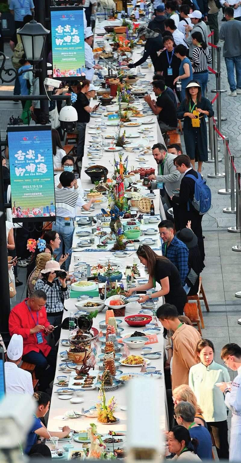 市民和游客在寧波舉辦的第三屆中國(guó)—中東歐國(guó)家博覽會(huì)暨國(guó)際消費(fèi)品博覽會(huì)上品嘗融合中國(guó)和中東歐美食的長(zhǎng)桌宴（2023年5月15日攝）。黃宗治攝/本刊