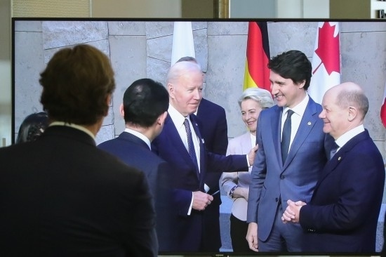 2022年3月24日，在比利時(shí)布魯塞爾的北約總部，一名男子觀看屏幕上美國總統(tǒng)拜登（右四）、歐盟委員會(huì)主席馮德萊恩（右三）、加拿大總理特魯多（右二）、德國總理朔爾茨（右一）出席七國集團(tuán)峰會(huì)合影儀式的畫面。新華社記者鄭煥松攝