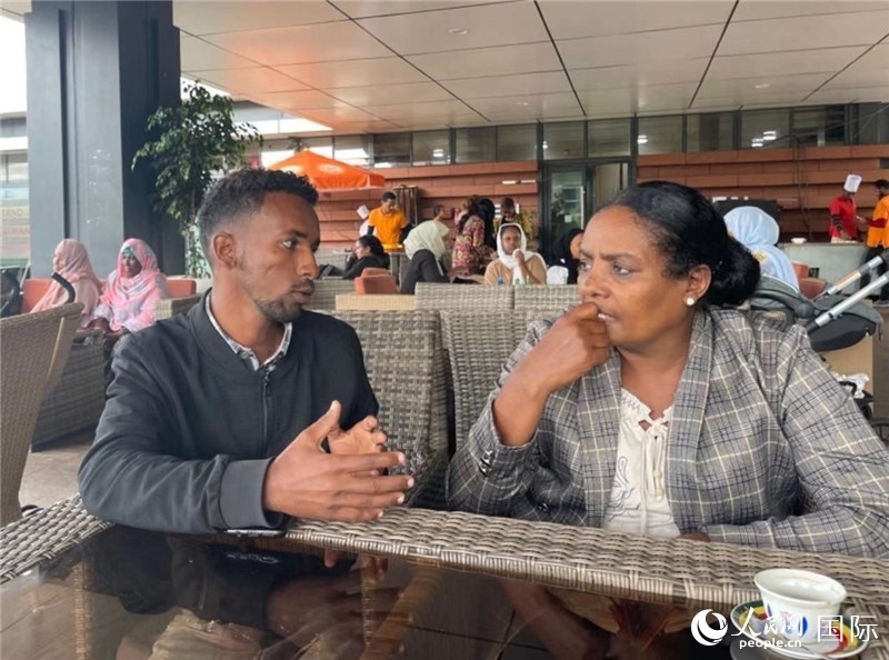 約漢斯（圖左）與德貝拉在友誼廣場(chǎng)咖啡廳交談。人民網(wǎng)記者 趙艷紅攝