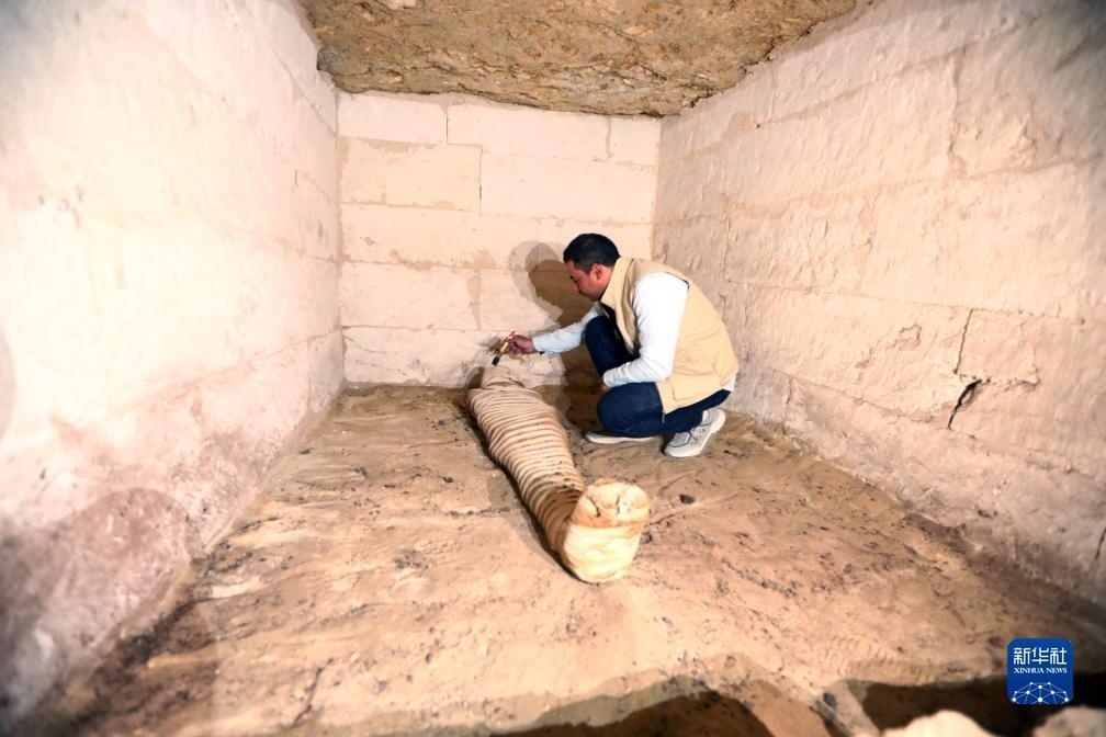 10月15日，在埃及明亞省考古現(xiàn)場，考古人員清理一座石鑿墓中的木乃伊。新華社發(fā)（艾哈邁德·戈馬攝）