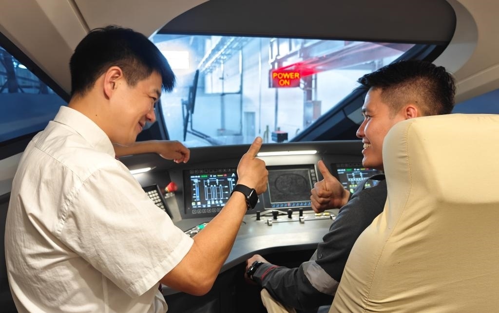 8月25日，在印度尼西亞萬隆的雅萬高鐵德卡魯爾動車所內(nèi)，中國師傅穆振（左）在向印尼火車司機塞蒂亞萬講解動車組出庫前的上電作業(yè)。