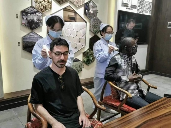 2023“一帶一路”媒體合作論壇聯合采訪團團員在九牛草展示館體驗艾灸。（本報記者 黃超攝）