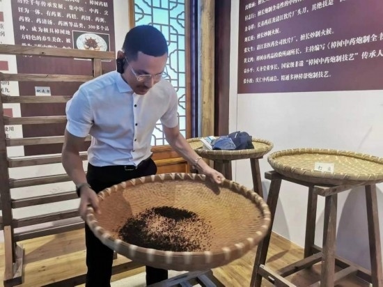 2023“一帶一路”媒體合作論壇聯合采訪團團員在非遺文化展示館體驗中藥炮制技藝。（本報記者 黃超攝）