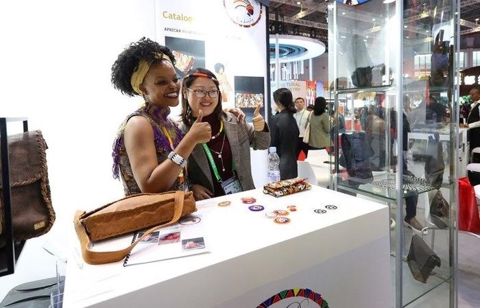 11月6日，一位參觀者（右）在第六屆進(jìn)博會國家展南非展臺試戴傳統(tǒng)首飾。