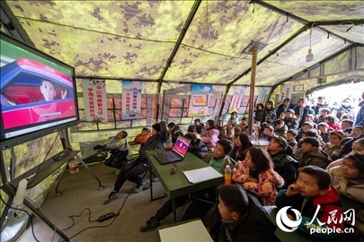 12月22日，在積石山縣大河家鎮(zhèn)大河村安置點，陸軍76集團軍某旅搭建的“臨時學?！眱?nèi)，小朋友正在看動畫片。人民網(wǎng)記者 翁奇羽攝