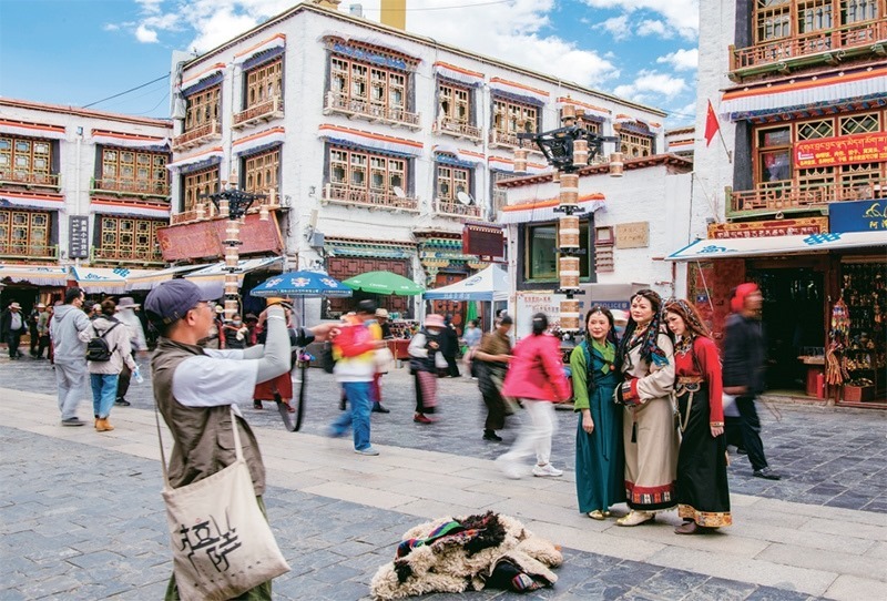 千年八廓街，見證民族團(tuán)結(jié)。2021年7月，習(xí)近平總書記來到位于西藏拉薩老城區(qū)的八廓街，感慨地說：“千年八廓街，是我們各民族建起來的八廓街。各民族文化在這里交流交往交融，我們中華民族的大家庭在這里其樂融融?！眻D為2023年6月13日，游客身著藏裝在八廓街拍照留念。 新華社記者 姜帆/攝