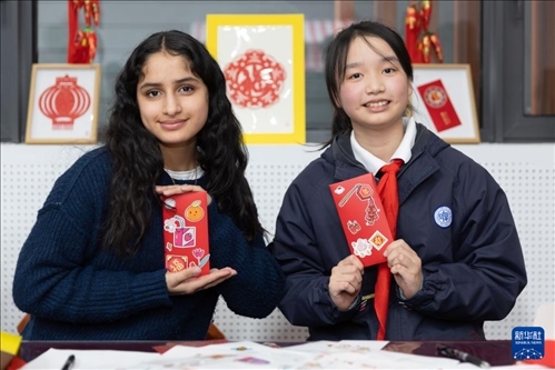 1月28日，美國馬斯卡廷中學學生（左）和復旦大學第二附屬學校學生展示互相送出的寫有寄語祝福的紅包。 新華社記者 王翔 攝