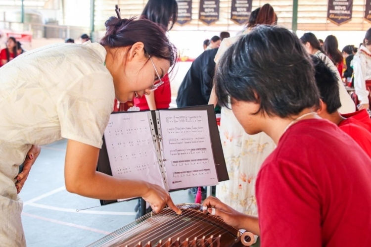 志愿者教師指導(dǎo)學(xué)生彈奏古箏?；顒又鬓k方供圖