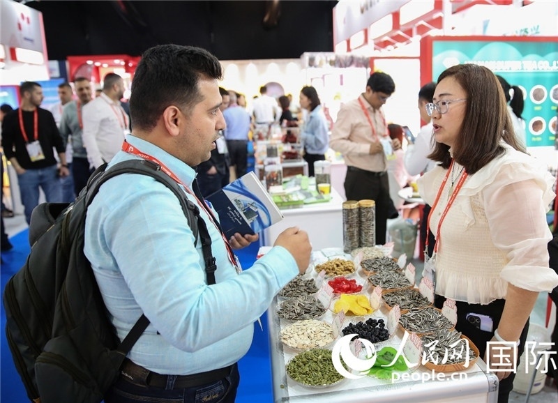 圖為一家中國干果參展企業(yè)代表與采購商洽談。人民網(wǎng) 塔里克·易卜拉欣攝