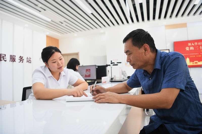 2023年5月23日，河北雄安新區(qū)容東片區(qū)南文營社區(qū)居民（右）在社區(qū)便民服務(wù)站辦理業(yè)務(wù)。