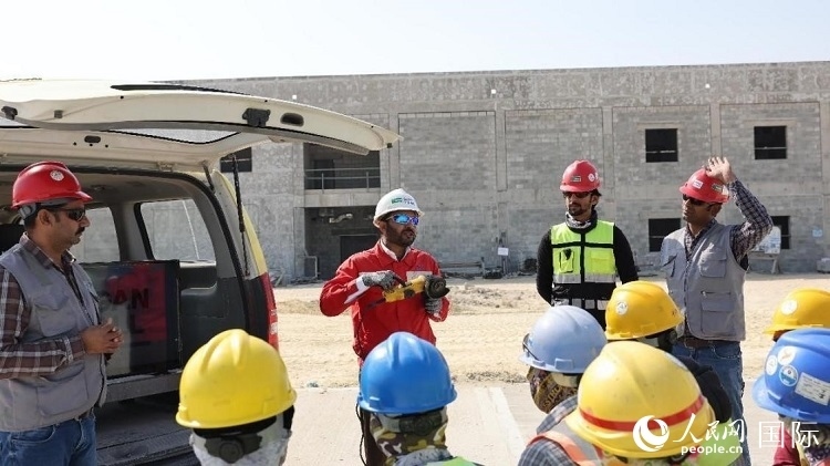 穆薩瓦爾(圖中紅衣人）現(xiàn)場演示工具操作規(guī)范。人民網(wǎng)記者 管克江攝