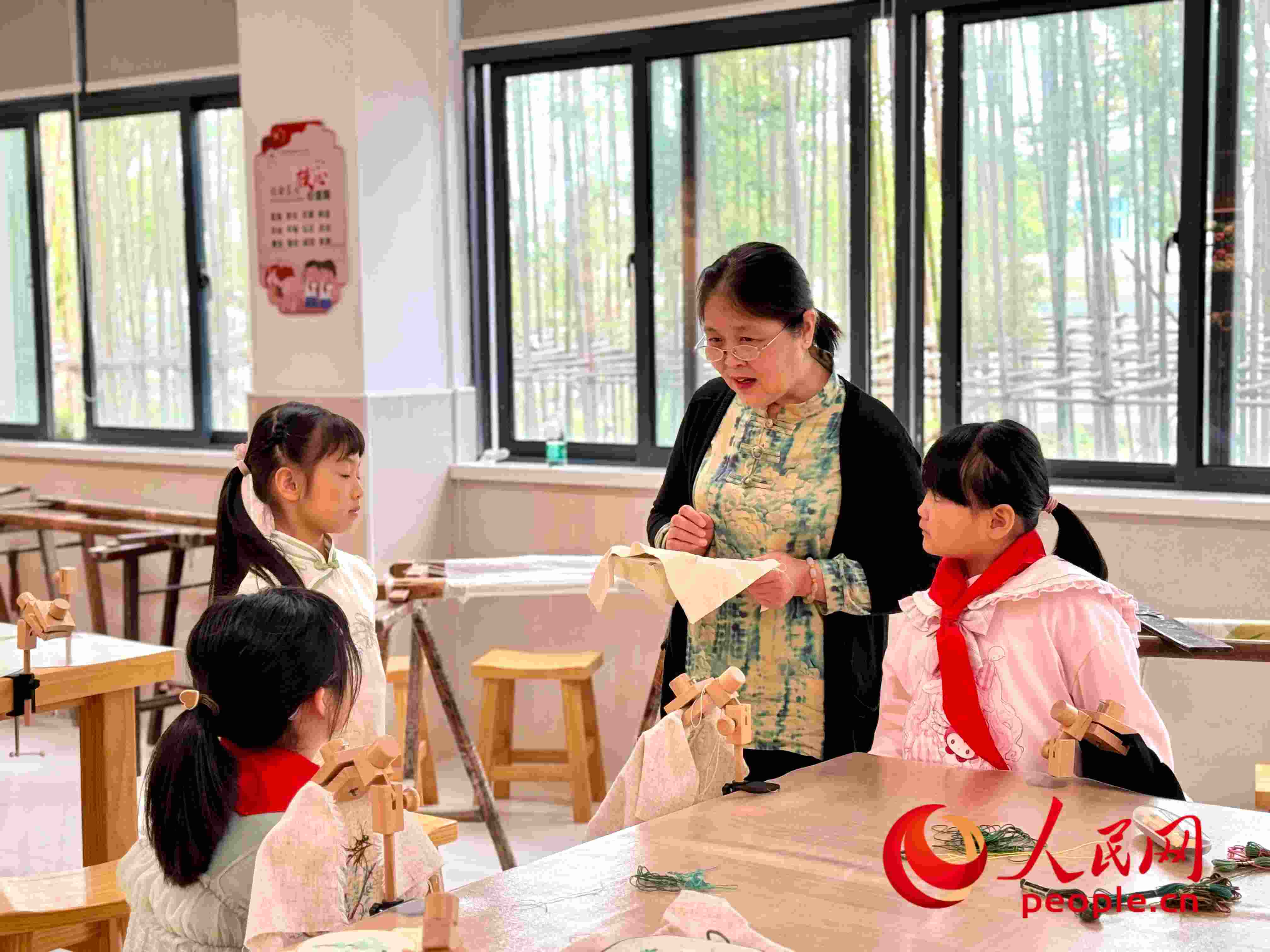 顧建珍（左三）在教孩子們刺繡知識。人民網(wǎng) 周靜圓攝