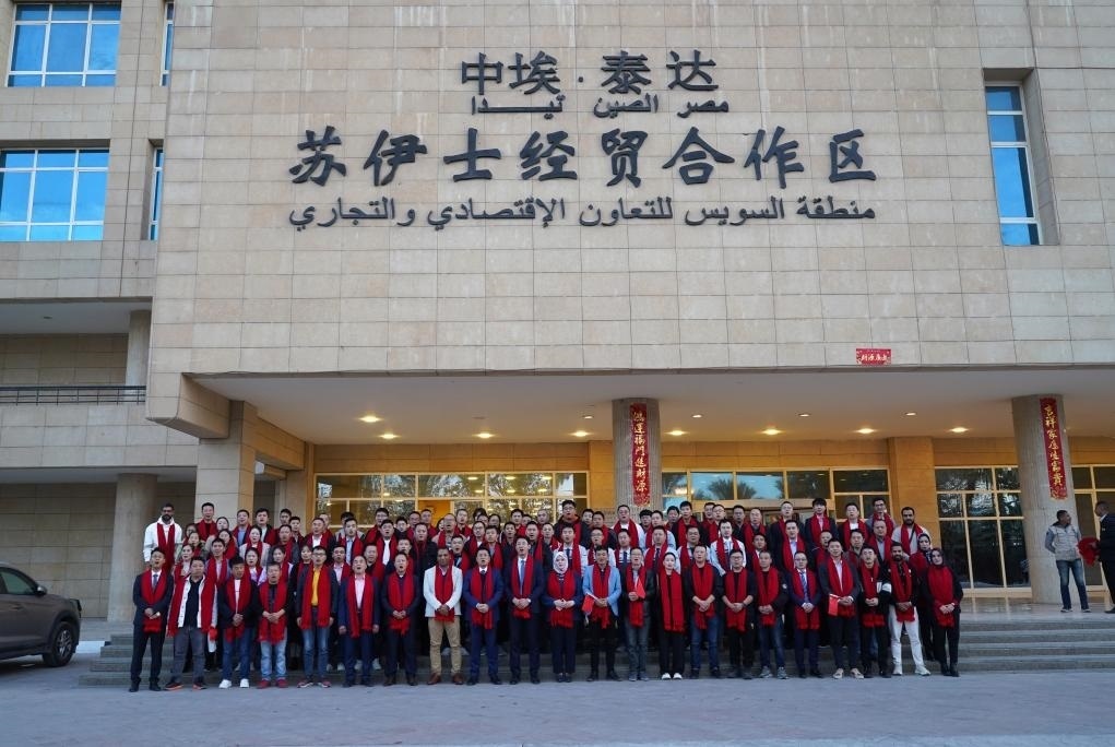 2024年2月11日，在位于埃及蘇伊士省的中?！ぬ┻_(dá)蘇伊士經(jīng)貿(mào)合作區(qū)，中埃員工在合作區(qū)辦公大樓前合影拜年。新華社發(fā)（泰達(dá)合作區(qū)供圖）