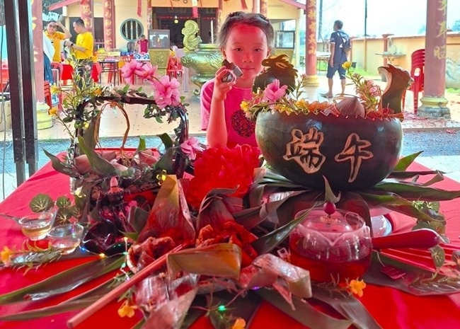 小朋友展示學(xué)裹粽子的成品照。組委會供圖