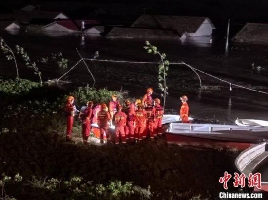  7月6日凌晨3時，在湖南岳陽華容縣團(tuán)洲垸洞庭湖一線堤防，救援人員剛剛完成一次救援任務(wù)，遠(yuǎn)處是被淹的民房。中新社記者 白祖偕 攝