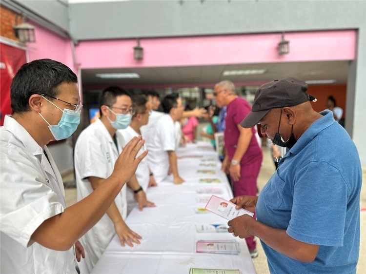 援圭醫(yī)療隊(duì)隊(duì)員們?cè)趩?dòng)儀式上為當(dāng)?shù)孛癖姺职l(fā)宣傳手冊(cè)。中國(guó)援助圭亞那醫(yī)療隊(duì)供圖