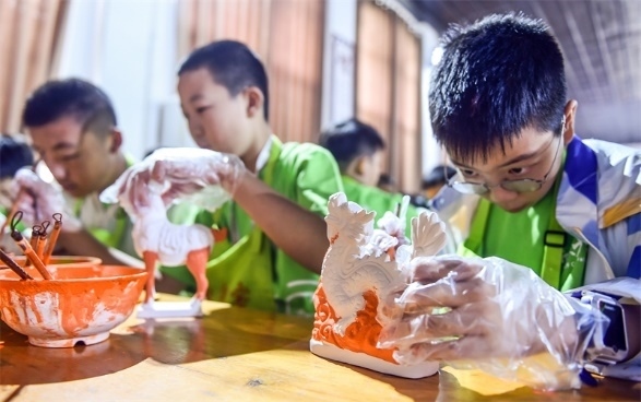 小朋友們在洛陽市孟津區(qū)朝陽鎮(zhèn)南石山村體驗唐三彩素胎施釉技藝。圖片來源：視覺中國