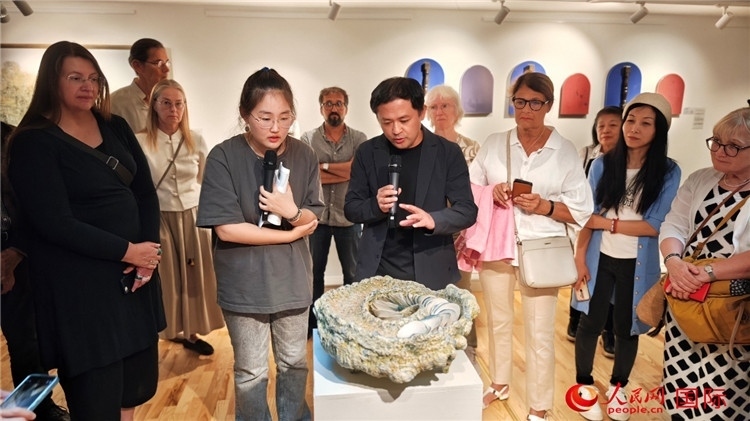 參展人、景德鎮(zhèn)陶瓷大學設(shè)計藝術(shù)學院副院長余劍峰（中）向來賓介紹參展作品。人民網(wǎng)記者 殷淼攝