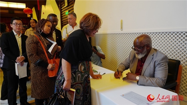 譚哲理在活動(dòng)現(xiàn)場簽名贈(zèng)書。人民網(wǎng) 劉暢攝