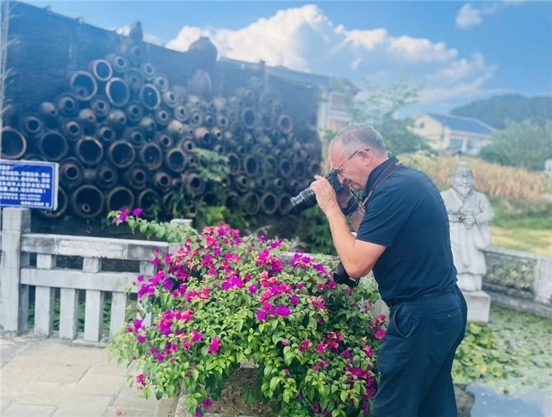 遠(yuǎn)處黔北民居錯落有致，近處一只黑色的蝴蝶穿梭于粉紫色三角梅花叢間隙，與俄羅斯“大歐亞”總編輯弗拉基米爾·別列日內(nèi)赫的鏡頭玩起了捉迷藏，“你追我逃，不亦樂乎”。（張亞欣攝）