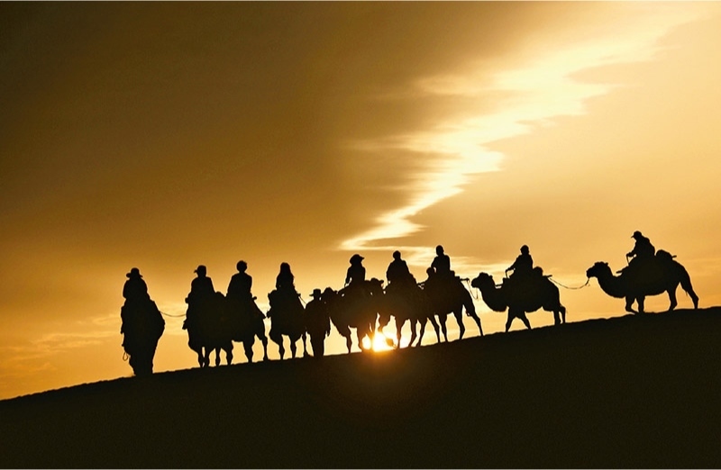 新時(shí)代以來(lái)，文化和旅游深度融合發(fā)展體制機(jī)制不斷健全，成功走出了一條獨(dú)具特色的中國(guó)旅游發(fā)展之路。圖為2024年9月1日清晨，游客在甘肅省敦煌市鳴沙山月牙泉景區(qū)乘騎駱駝，欣賞大漠風(fēng)光，體驗(yàn)絲路風(fēng)情。 新華社發(fā) 張曉亮/攝