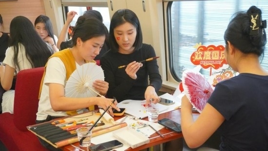 10月1日，旅客們?cè)贕1634次列車上給油紙傘作畫。新華社記者周義 攝