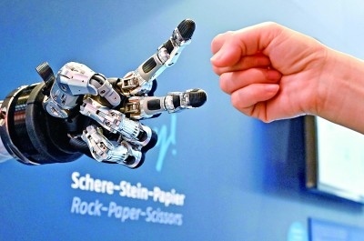 在德國漢諾威工博會上，參觀者與一款智能機(jī)器人進(jìn)行“石頭剪子布”游戲。新華社發(fā)