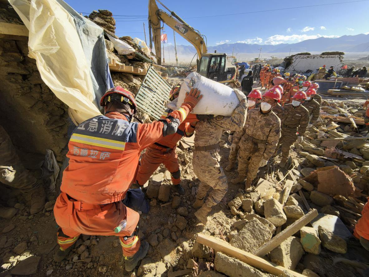 1月11日，定日縣長所鄉(xiāng)古榮村，應(yīng)急消防等救援人員排隊接力搶運(yùn)掩埋在倒塌房屋下的群眾財物。人民日報記者楊翹楚攝