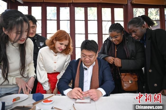 1月20日，篆刻家王臻向外籍留學(xué)生展示篆刻印章。當(dāng)日，來自巴西、馬來西亞、加納、哈薩克斯坦的外籍留學(xué)生在浙江杭州西泠印社體驗(yàn)福貼、春聯(lián)和篆刻，感受古老的中國傳統(tǒng)文化。中新社記者 王剛 攝