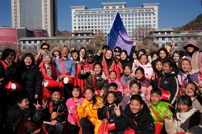 中外青年學(xué)子在安塞文化廣場觀看陜北腰鼓和大秧歌表演后合影留念，大家踏著鼓點(diǎn)共舞，翻飛的紅綢與躍動的身影交織，在黃土地廣場上繪出一幅生動的陜北民俗互動畫卷