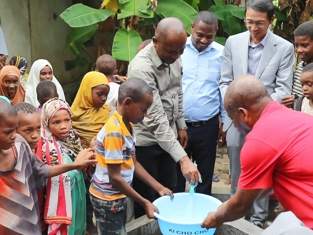 在日前舉行的安全供水工程揭牌儀式上，當(dāng)?shù)匦∨笥言诠┧c(diǎn)接水。 施亮攝